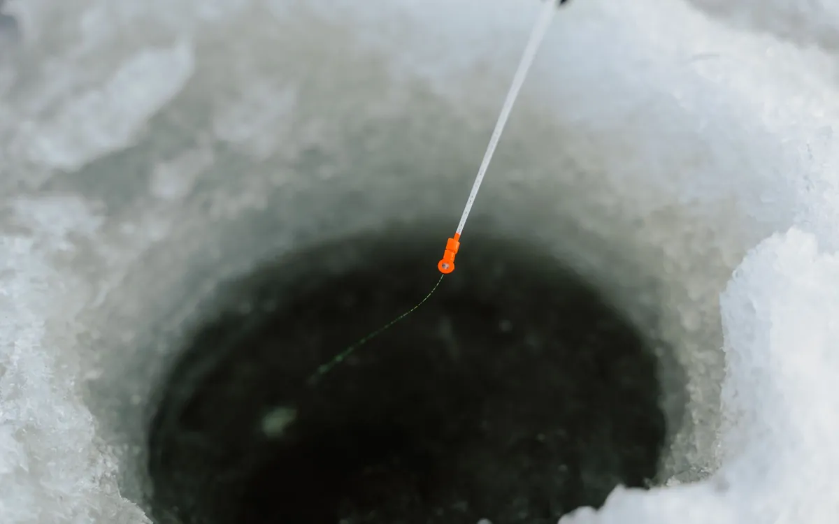 Short ice fishing rod over a hole drilled in the ice